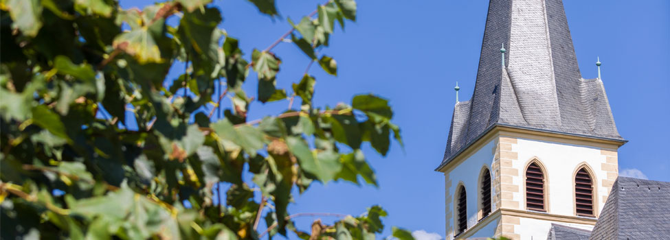 Detail eines Kirchturms vor blauem Himmel